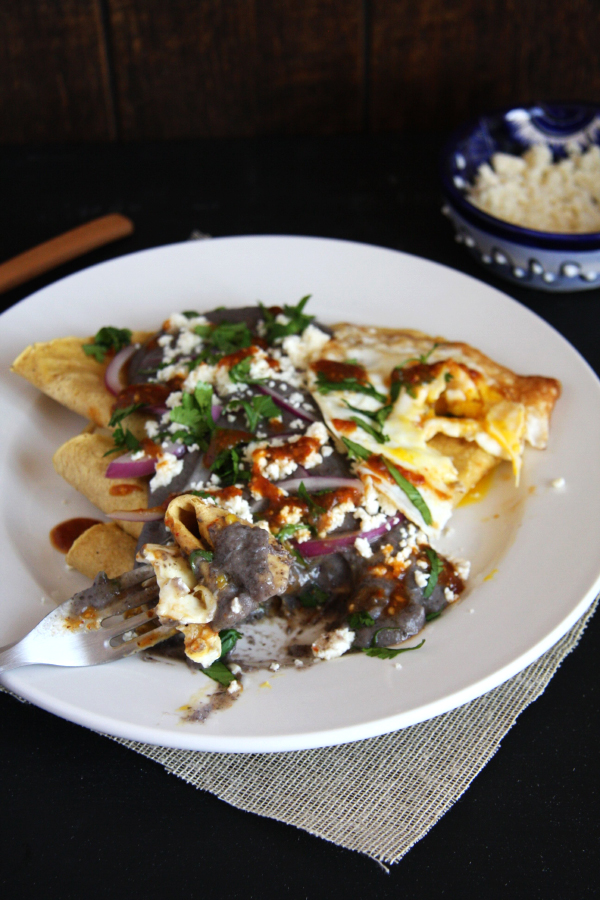 Classic Mexican Enfrijoladas- tortillas bathed in a flavorful black bean sauce and topped with cheese, red onion, cilantro, salsa and a fried egg. #mexican